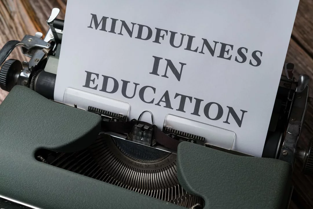 Eine Schreibmaschine mit einem Blatt Papier, auf dem in Großbuchstaben "MINDFULNESS IN EDUCATION" steht, was die Bedeutung von Achtsamkeit und Achtsamkeitsübungen im Lernprozess hervorhebt.