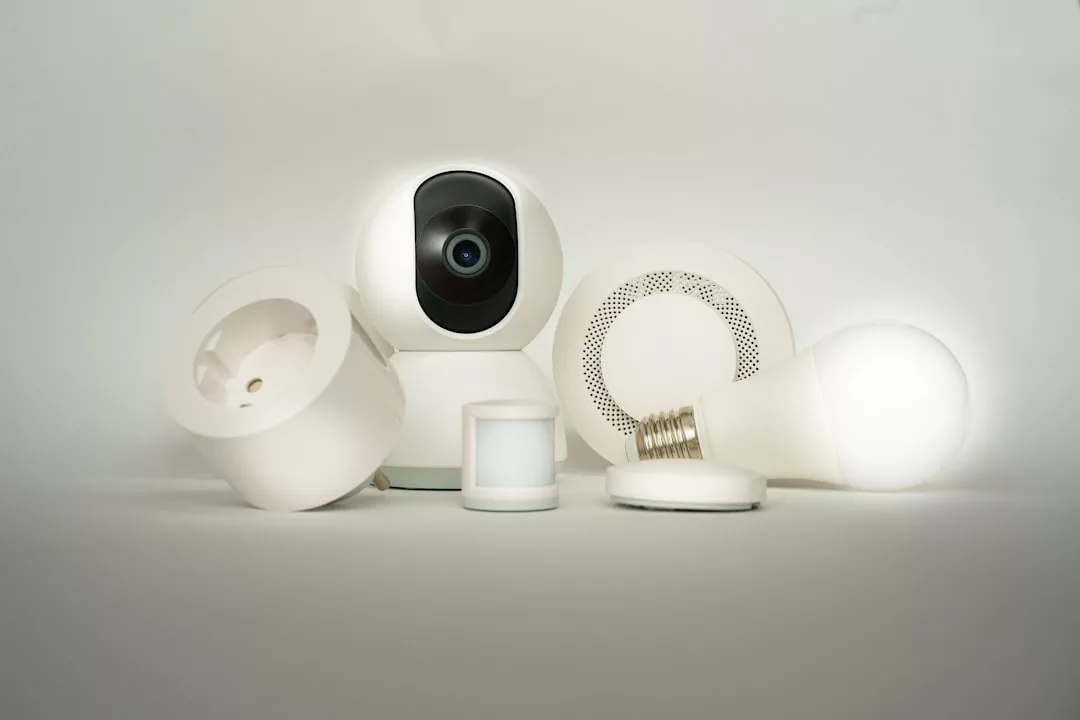 Eine Gruppe von effizienten Technologie Smart-Home-Geräten, darunter Sicherheitskamera, Smart Plug, Sensor, Rauchmelder und smarte Glühbirne, arrangiert auf weißer Oberfläche - perfekt für automatisierte Heimsysteme im Zuhause.