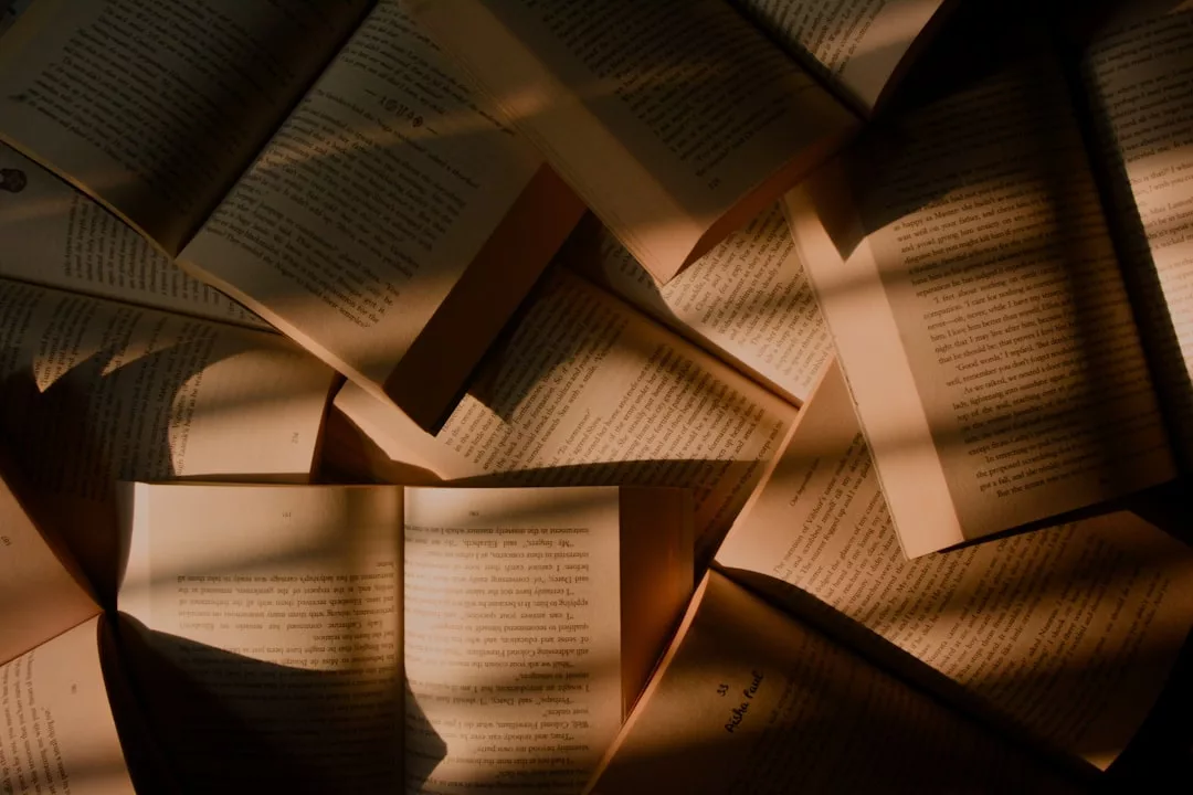 Mehrere aufgeschlagene Bücher liegen übereinander, und das sanfte Sonnenlicht wirft Schatten auf die Seiten - perfekt, um inspirierende Bücher und neue Bücherempfehlungen zu entdecken.