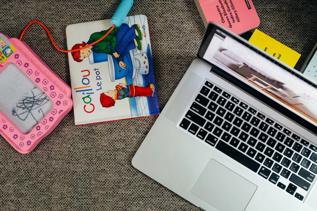 Ein Kinderbuch, ein Zeichentablett und ein Laptop liegen auf dem Teppichboden, zusammen mit einigen anderen Papieren und Gegenständen - perfekt, um Tipps und Tricks zu notieren, wenn Sie bereit sind, einen Blog über kreative Inspiration zu starten.