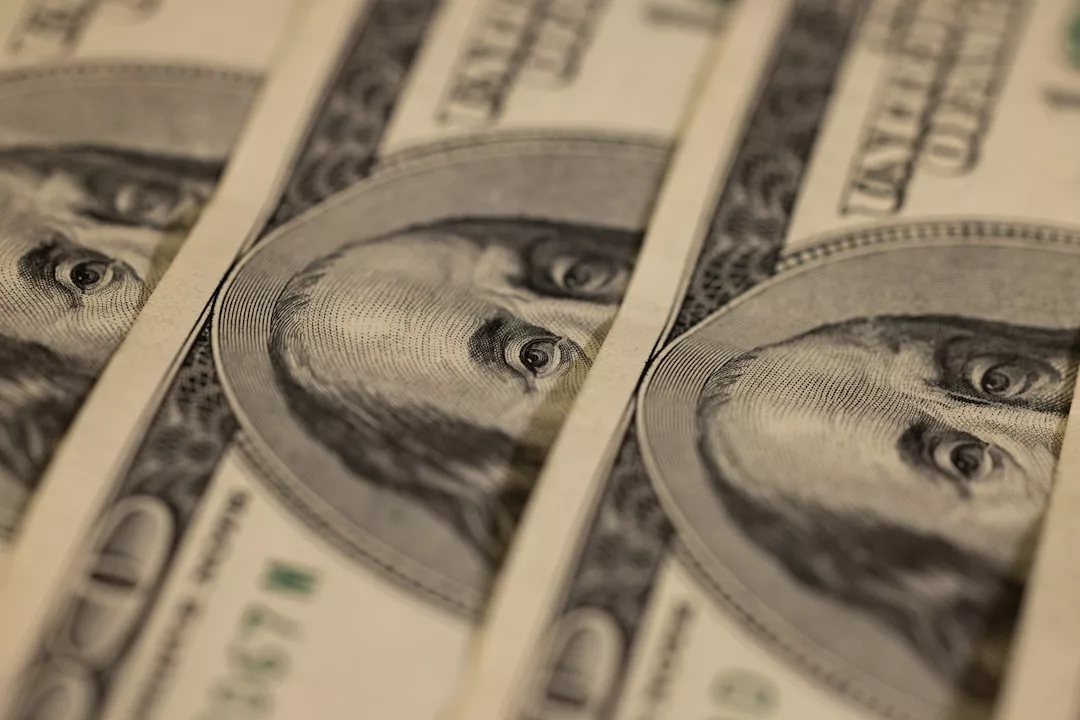 Nahaufnahme mehrerer parallel angeordneter Hundert-Dollar-Scheine, auf denen jeweils ein Teil des Porträts von Benjamin Franklin abgebildet ist - ein eindrucksvolles Bild für eine Analyse der Auswirkungen der Inflation.