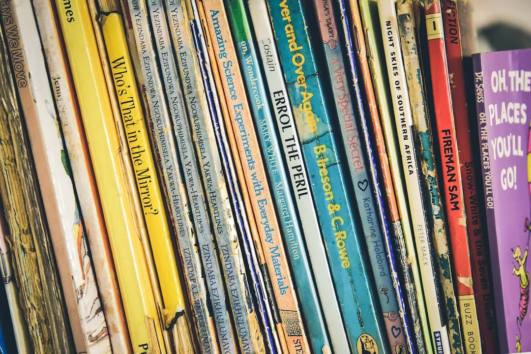 Eine Nahaufnahme von Kinderbüchern, die aufrecht in einem Regal stehen, mit bunten Buchrücken, auf denen verschiedene Titel und Autoren zu sehen sind - perfekt für die Erziehung und zur Anregung junger Menschen.