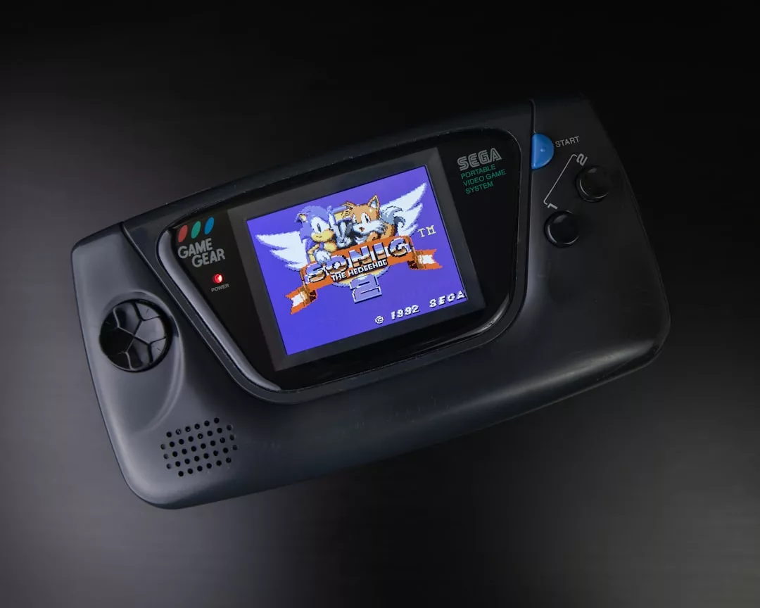Eine Sega Game Gear Handheld-Konsole zeigt den Titelbildschirm für das Spiel "Sonic the Hedgehog 2" mit Sonic und Tails, das die Faszination von Retro Games einfängt.