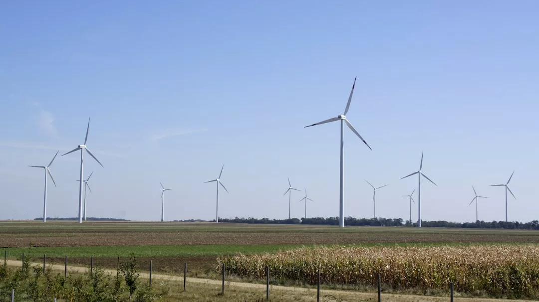 Mehrere Windkraftanlagen stehen in einer offenen, ländlichen Landschaft mit Feldern und klarem Himmel und zeigen die neuesten Windkraft Entwicklungen in nachhaltiger Energieerzeugung.