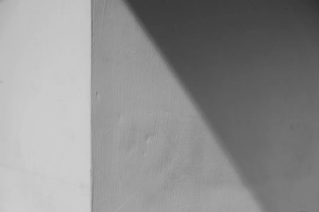 Eine strukturierte Wand mit einem scharfen diagonalen Schatten, der helle und dunkle Bereiche trennt, erinnert an die Psychologie des Sparens - ähnlich wie sorgfältiges Sparverhalten den Kontrast zwischen Ausgaben und Geld zurückhalten hervorhebt.