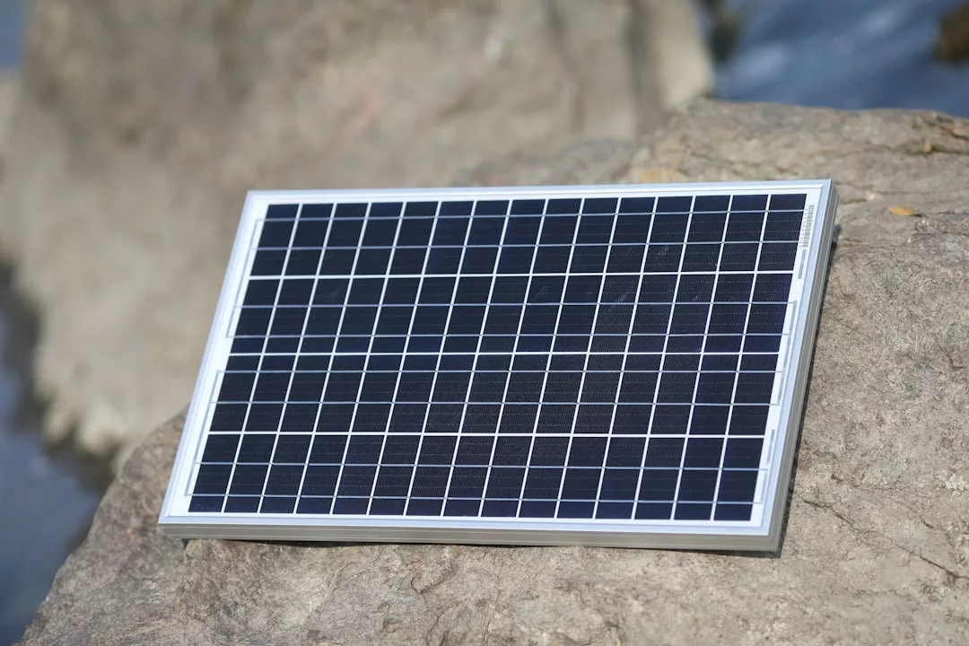 Ein kleines rechteckiges Solarmodul mit einem Gittermuster ist auf einem großen Felsen im Freien platziert, um auf innovative Umweltlösungen hinzuweisen, die den Weg für eine nachhaltige Wirtschaft und zukünftige Solarfarmen ebnen.