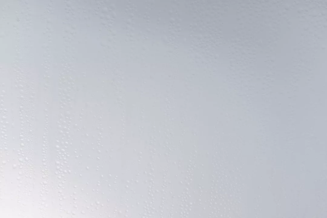 Nahaufnahme einer nebligen oder mattierten Glasoberfläche, die mit kleinen Wassertröpfchen gesprenkelt ist und an die erfrischende Klarheit erinnert, die mit gesunder Ernährung und effektiver Diät einhergeht.