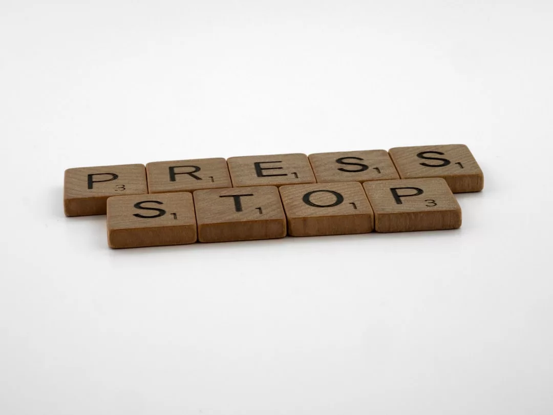 Hölzerne Scrabble-Steine buchstabieren die Worte "PRESS STOP" auf einem schlichten weißen Hintergrund und erinnern uns an Stressbewältigung und Tipps, um im Alltag bewusst eine Pause einzulegen.