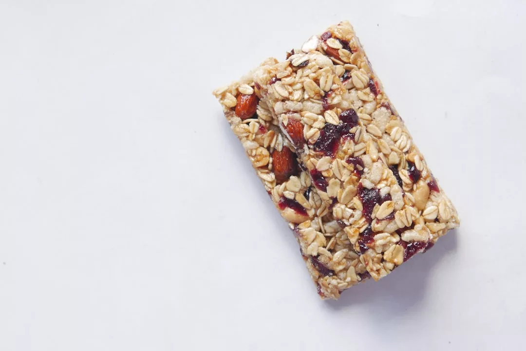 Zwei Müsliriegel mit Haferflocken, Nüssen und Trockenfrüchten sind auf einer schlichten weißen Fläche platziert - ideal für effektives Abnehmen und gesundes Snacken.