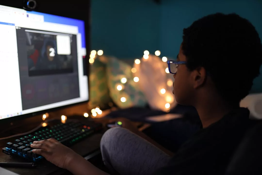 Eine Person sitzt an einem Schreibtisch mit einem Computer in einem schwach beleuchteten, mit Lichterketten geschmückten Raum und begrüßt das E-Learning als Teil der Zukunft des Lernens.