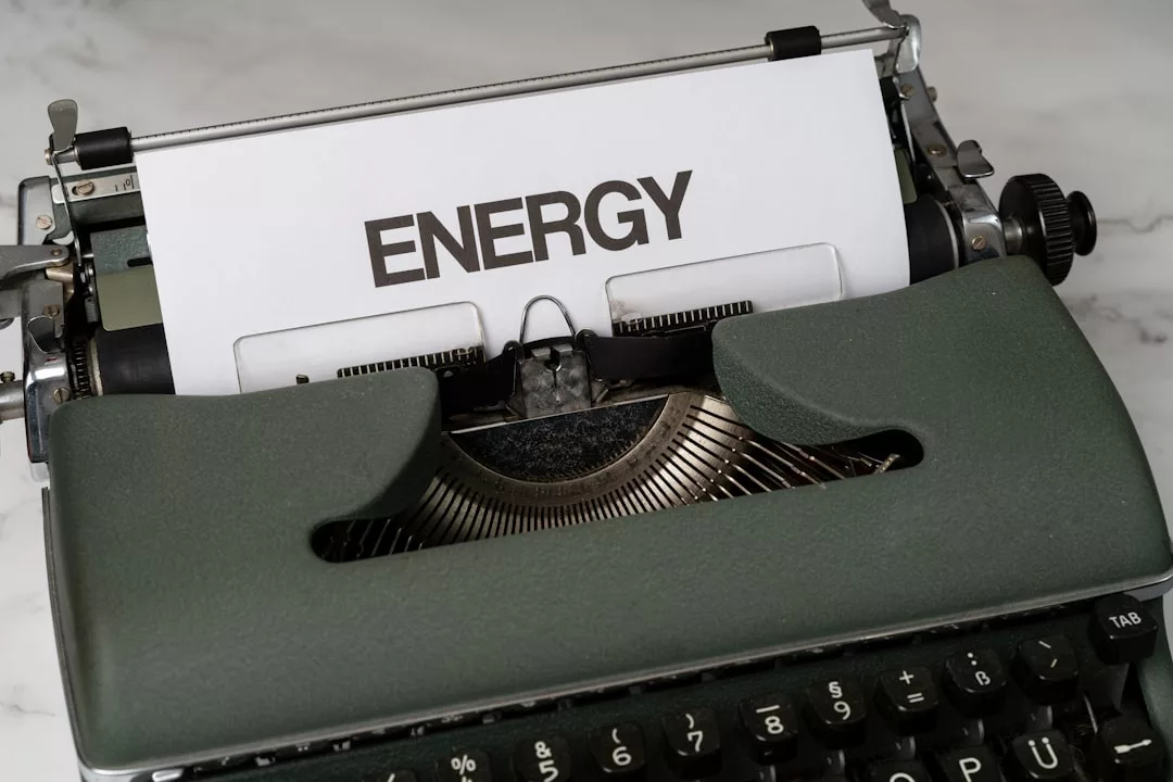 Ein Blatt Papier mit dem Wort "ENERGY" ist auf einer weißen Fläche in eine alte Schreibmaschine eingelegt und symbolisiert, wie wir Energieverbrauch in unserem täglichen Leben effektiv reduzieren können.