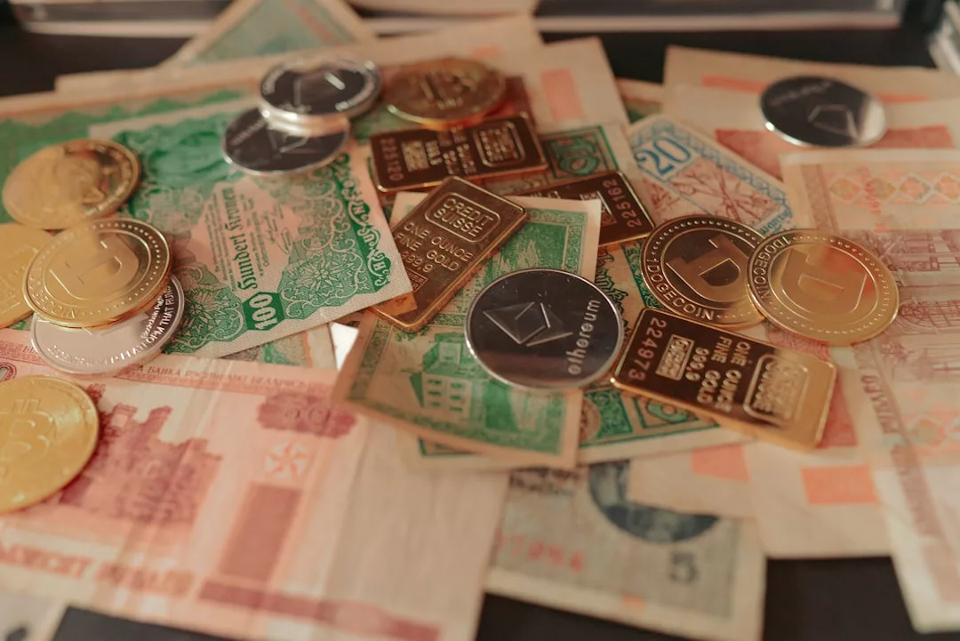 Verschiedene Papierwährungen und Münzen, darunter Goldbarren und Kryptowährungs-Token, sind auf einer Fläche verstreut - Symbole für finanzielle Sicherheit und eine sorgenfreie Zukunft im Alter.