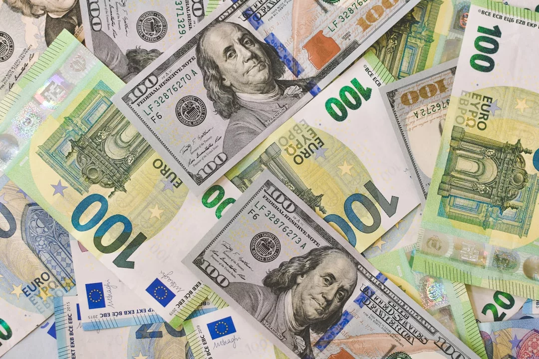 Ein Stapel sich überlappender 100-US-Dollar- und 100-Euro-Scheine, die die unterschiedlichen Designs und Farben beider Währungen zeigen, spiegelt die Auswirkungen der Inflation auf die globale Wirtschaft wider.
