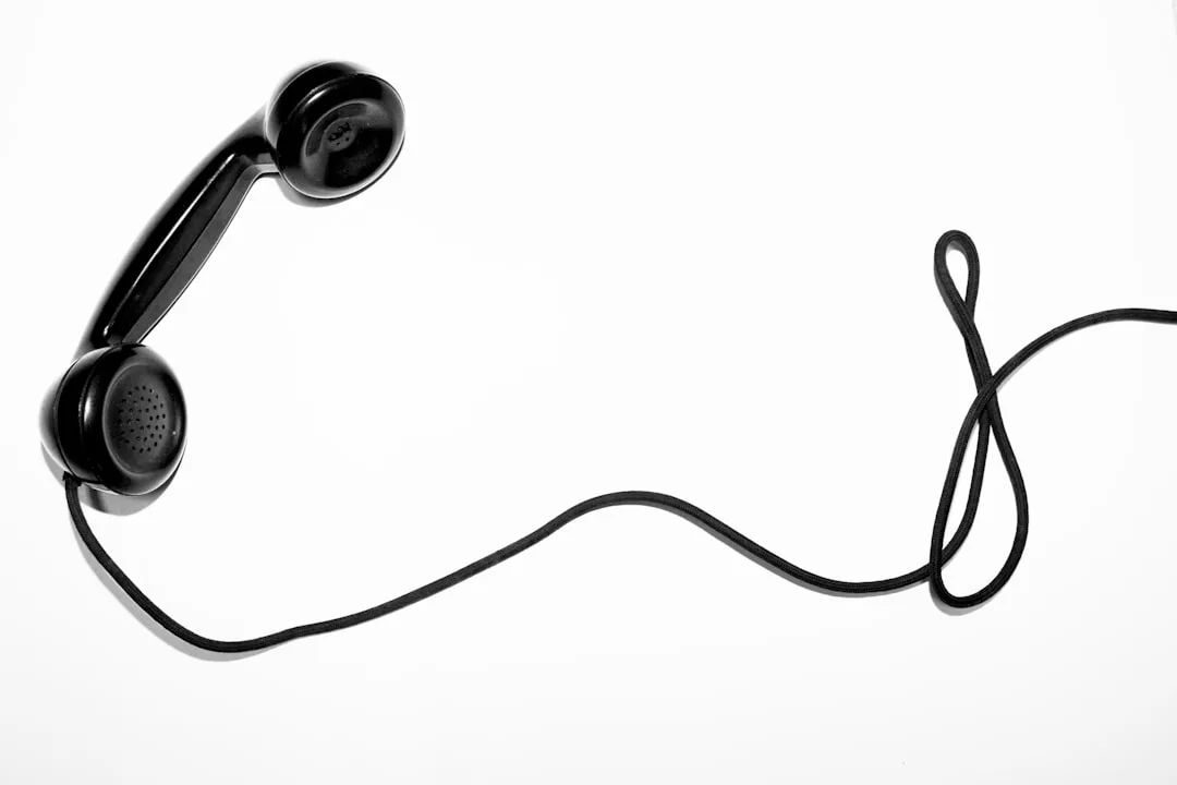 Auf einer weißen Fläche liegt ein schwarzer Telefonhörer, dessen aufgewickeltes Kabel locker nach rechts gespannt ist - ein Symbol für die auf Vertrauen aufgebaute Kommunikation.