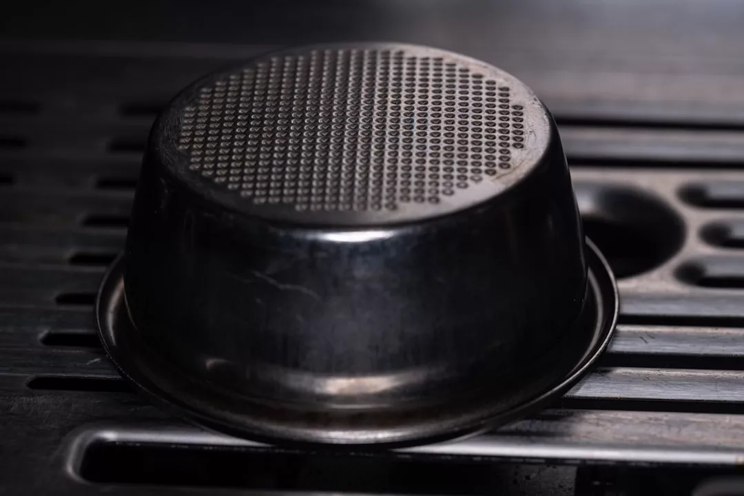 Ein Schnellkochtopf aus Metall steht kopfüber auf einem schwarzen Geschirrständer und zeigt seinen gemusterten Boden - perfekt für die Zubereitung köstlicher Schnellkochtopf-Rezepte.