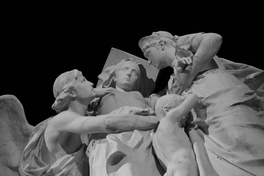 Drei Marmorstatuen, darunter zwei Erwachsene und ein Kind, werden in enger Interaktion vor einem soliden schwarzen Hintergrund gezeigt - und fangen die Vielfalt kultureller Schätze in einer ausdrucksstarken Szene ein.