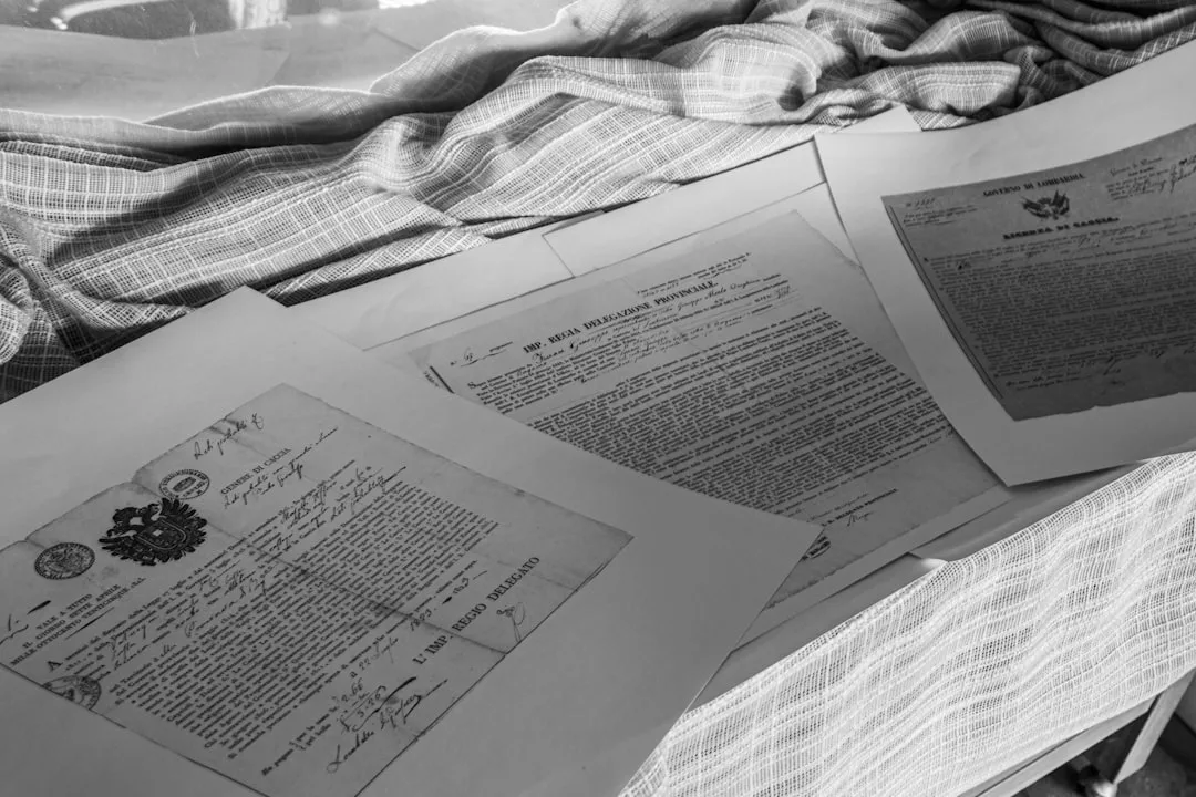 Schwarz-Weiß-Foto mehrerer offizieller Dokumente mit Unterschriften und Stempeln, ausgebreitet auf einer mit Stoff bezogenen Fläche - die perfekte Inspiration für Motivation im Studium und Tipps zum Erfolg.