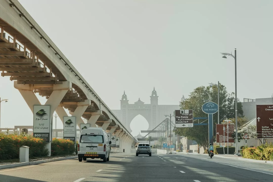 Eine Straße in Dubai mit Autos und einem Motorrad, links eine Einschienenbahn und im Hintergrund das Hotel Atlantis - perfekt für deine Roadtrip-Reise mit hilfreichen Tipps zur Planung.