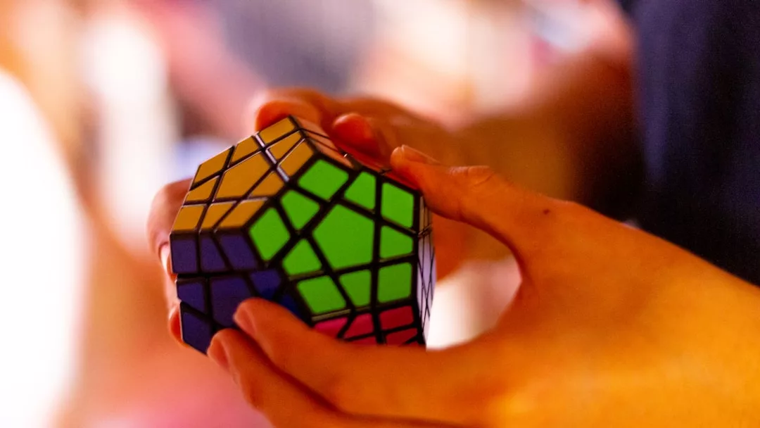 Eine Person hält und dreht ein buntes dodekaederförmiges Puzzle und zeigt ihre Fähigkeiten zur Problemlösung mit diesem Rubik's Cube-ähnlichen Rätsel lösen.