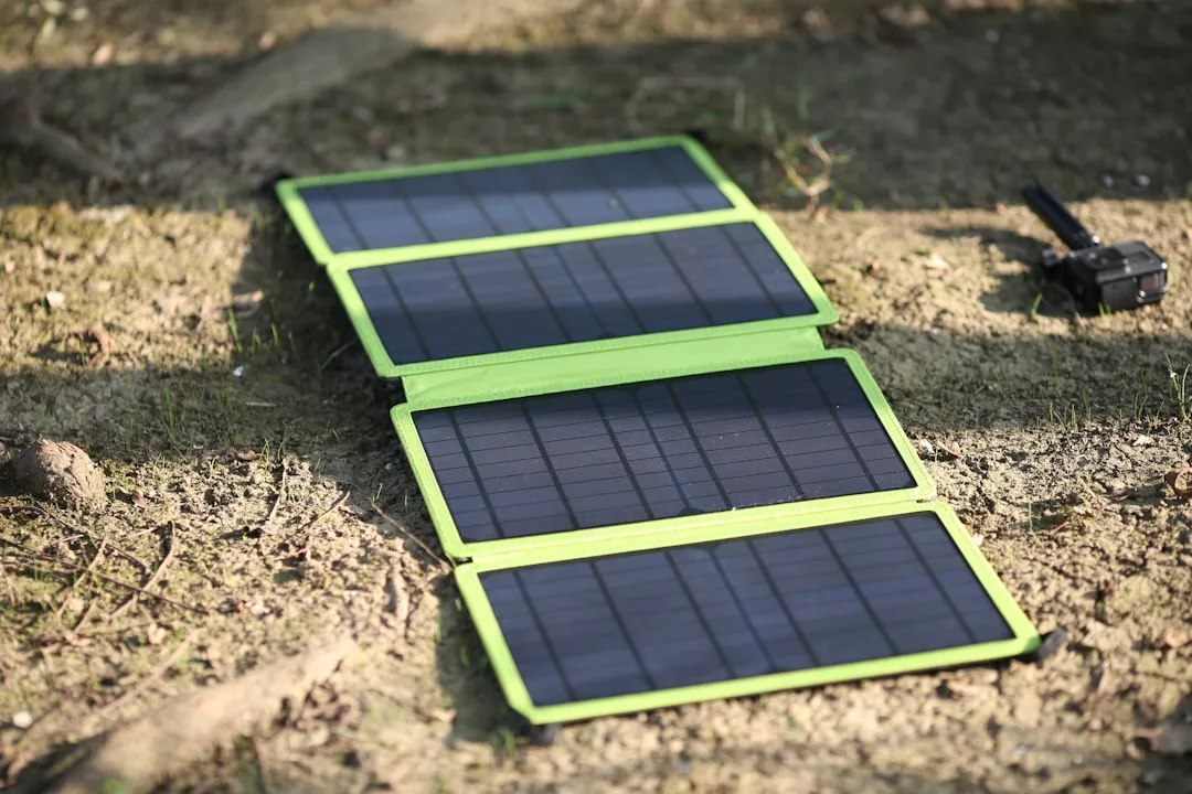 Ein tragbares, grün umrandetes Solarladegerät mit vier Paneelen liegt im Freien auf trockenem Boden und absorbiert das Sonnenlicht - und verdeutlicht damit die Bedeutung des Recyclings von Solarpaneelen für nachhaltige Entsorgung und Umweltschutz.