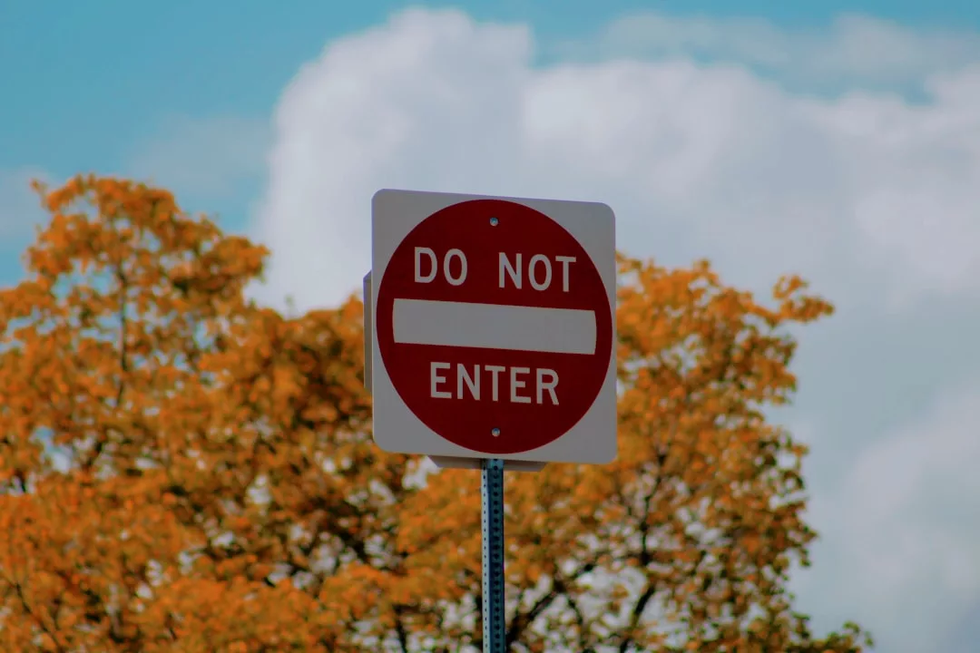 Ein rot-weißes "Betreten verboten"-Verkehrsschild ist vor Bäumen mit Herbstlaub und einem teilweise bewölkten Himmel abgebildet und erinnert Abenteuerreisen-Enthusiasten an wichtige Sicherheitsmaßnahmen.