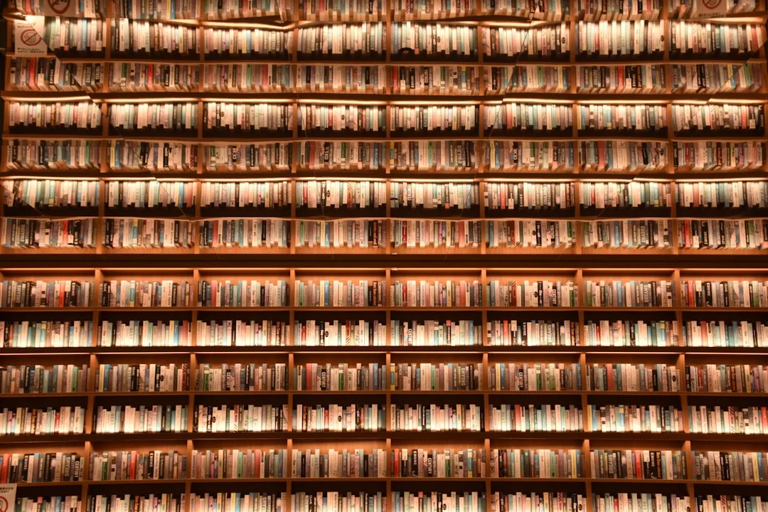 Reihen von Büchern füllen hohe, warm beleuchtete Regale in einer Bibliothek oder einer Buchhandlung, jeder Buchrücken bietet einen Einblick in die Bedeutung und den Einfluss von Weltliteratur über Generationen hinweg.
