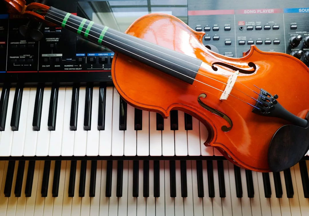 Eine Geige ruht auf den Tasten eines Digitalpianos, im Hintergrund ist ein Teil eines Synthesizer-Panels zu sehen - perfekt für diejenigen, die ein Musikinstrument wählen oder ein neues Instrument lernen möchten.